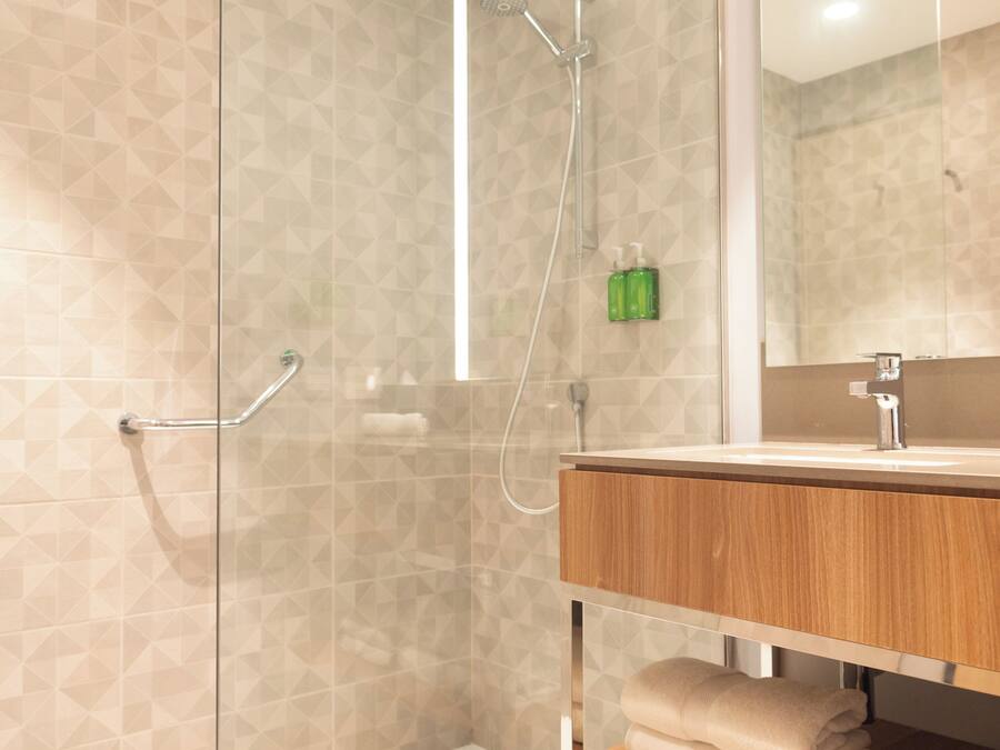 A modern bathroom with a glass shower enclosure, a wooden vanity, and a mirror.
