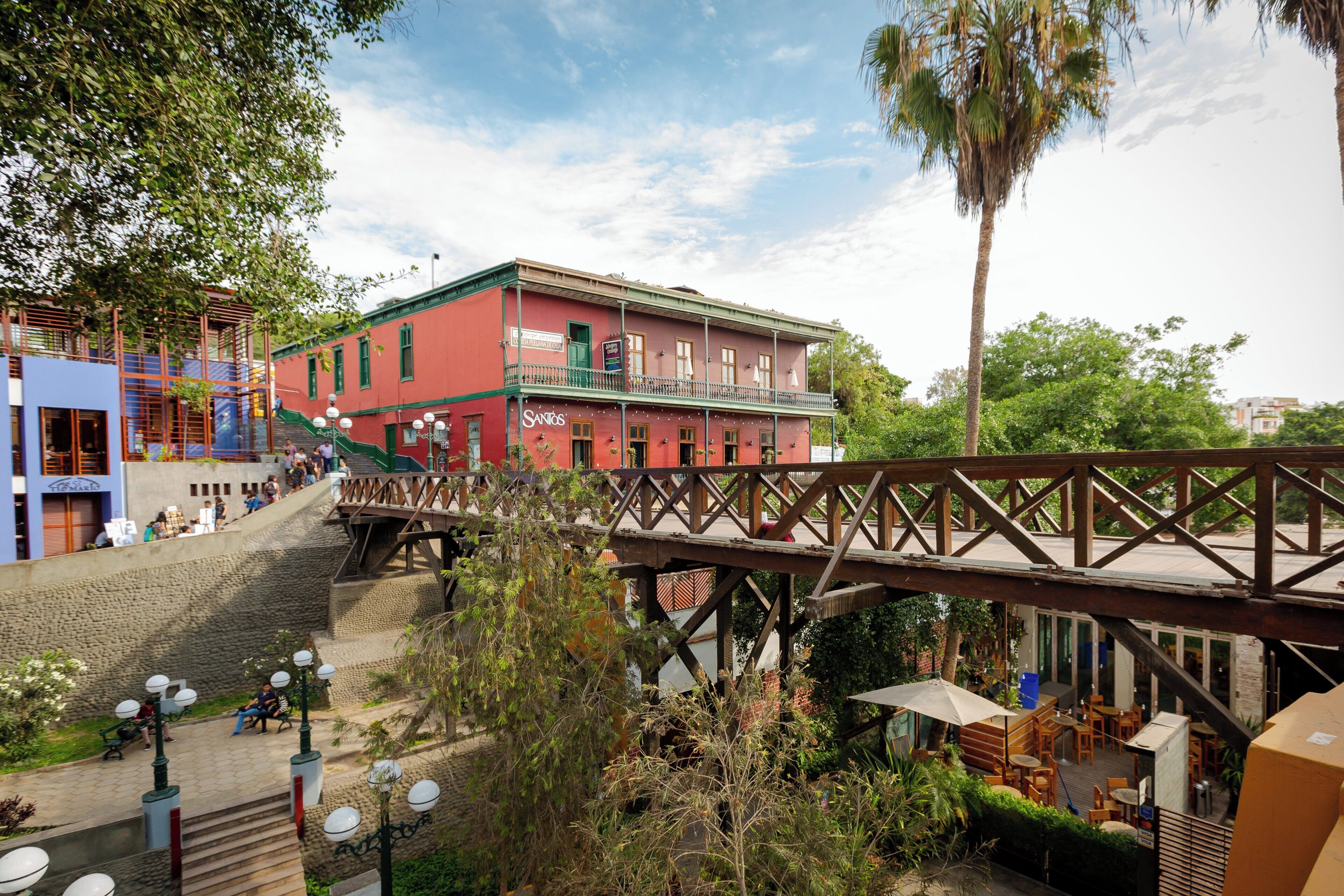 Un edificio rojo con un balcón, un puente de madera y asientos exteriores.