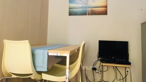 A room with a desk, two chairs, a TV, and a wall-mounted picture. - Staycation at smdc grass residences (Quezon city)