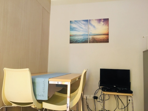 A room with a desk, two chairs, a TV, and a wall-mounted picture.
