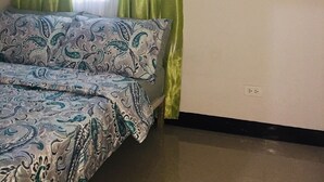 A bedroom with a bed, green curtains, a window with blinds, and an air conditioning unit. - Staycation at smdc grass residences (Quezon city)