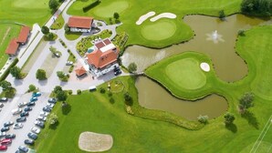 Vista aérea de un campo de golf con búnkeres, estanques y un club house.