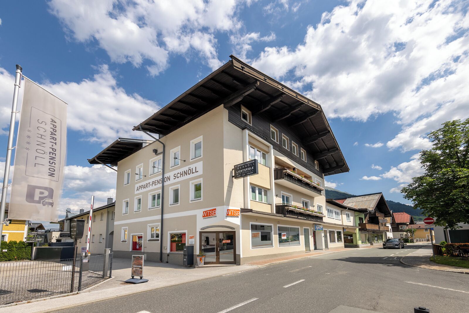 A multi-story building with a flat roof and a sign for 'Appart-Pension Schnöll'.