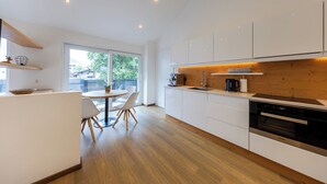 Una cocina moderna con armarios blancos, encimera de madera y un comedor con una mesa redonda y sillas.