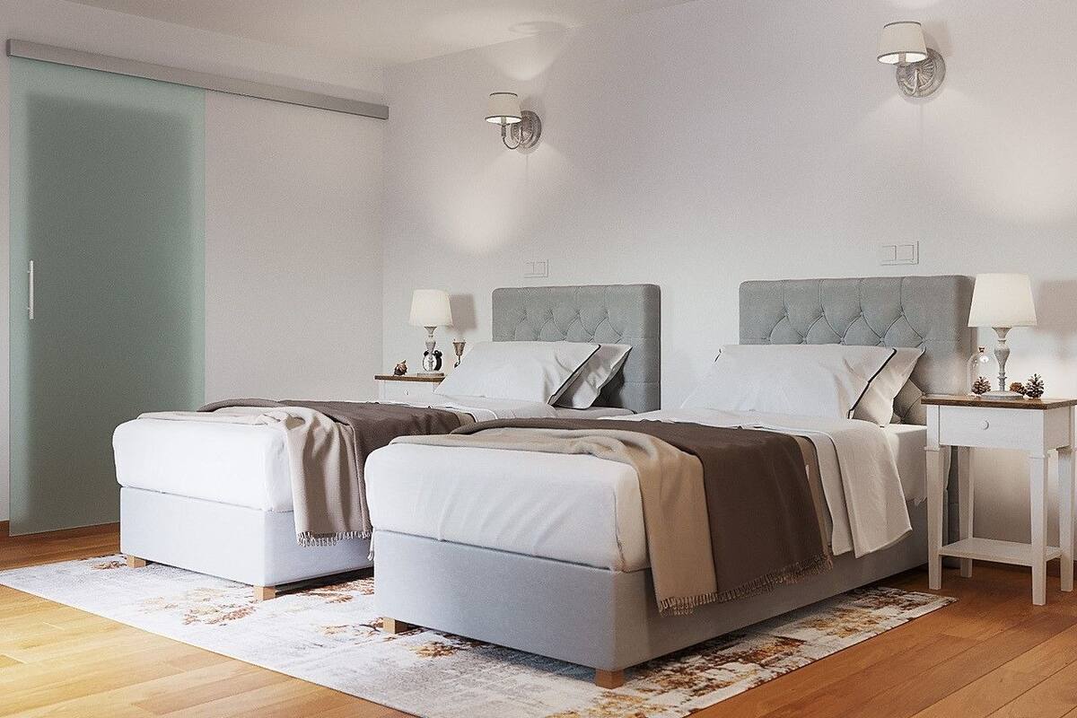 A double bed room with two bedside tables, each with a lamp, and a large window with a view of the outside.