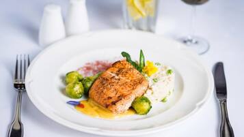 A plate with a piece of grilled fish, green vegetables, and a creamy sauce.