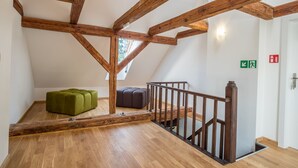 A loft-style room with exposed wooden beams, a wooden staircase, and two ottomans. - Oficyna przy Pałacu Krobielowice (Katy Wroclawskie)