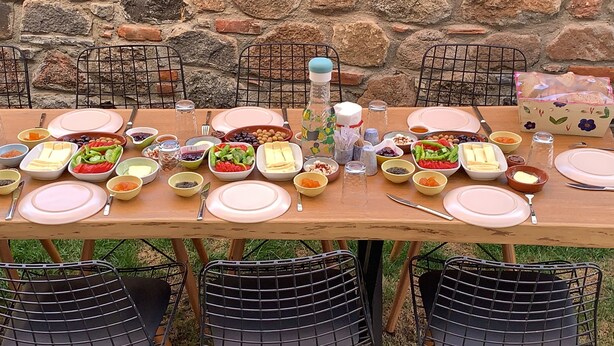 Una mesa de madera dispuesta para una comida, con diferentes platos y utensilios.