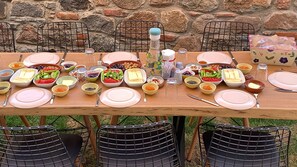 Una mesa de madera dispuesta para una comida, con diferentes platos y utensilios.