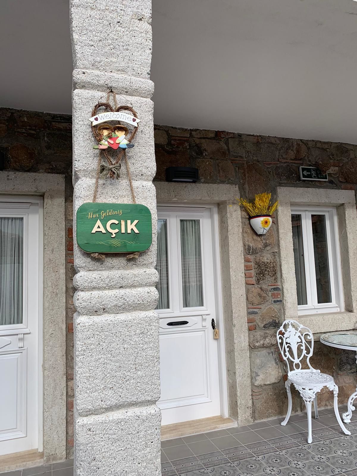 A stone pillar with a green sign reading "ACIK" and a welcome sign above it.