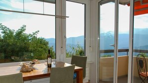 A dining area with a table, chairs, and a bottle of wine. - Residenza Monte Bré - Apt.004 Haus1 by Interhome (Aldesago)