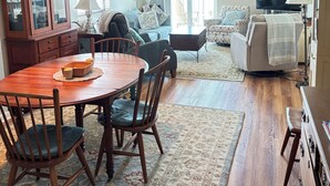A dining area with a wooden table and chairs, a cabinet with glass doors, and a television in the background. - Oceanfront condo w/direct beach access & 180 degree views from your private deck (Garden City Beach)