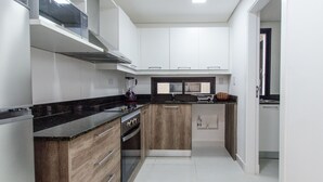 A modern kitchen with a black countertop, wooden cabinets, and a built-in oven. - Barrio Jara's Best Choice (Asunción)