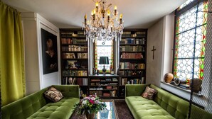 Una sala de estar acogedora con sofás verdes, una araña y una estantería llena de libros.
