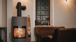 Una sala moderna con una estufa de leña, un sofá de cuero y un ventanal decorativo.