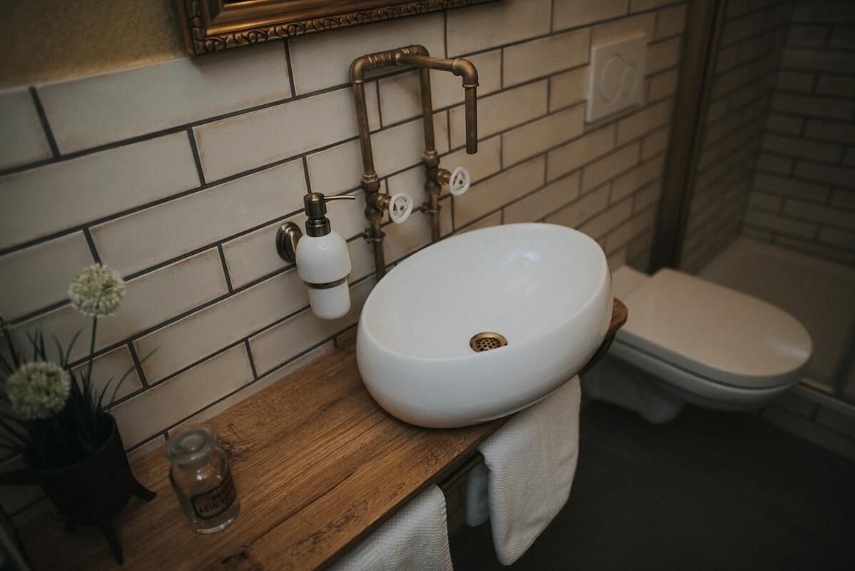 Et badeværelse med en hvid vask, træbordplade og et hvidt toilet.