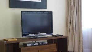 A wooden entertainment center with a flat-screen TV, a remote, and a DVD player. - Sheema Villas (Nairobi)
