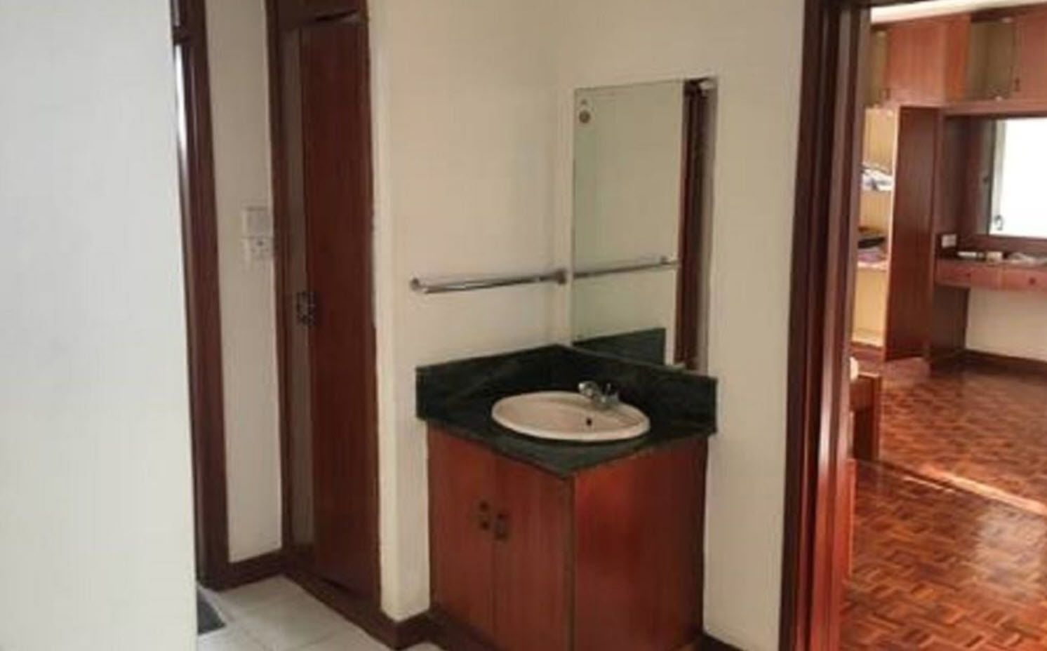 A bathroom with a wooden vanity, a sink, and a mirror.
