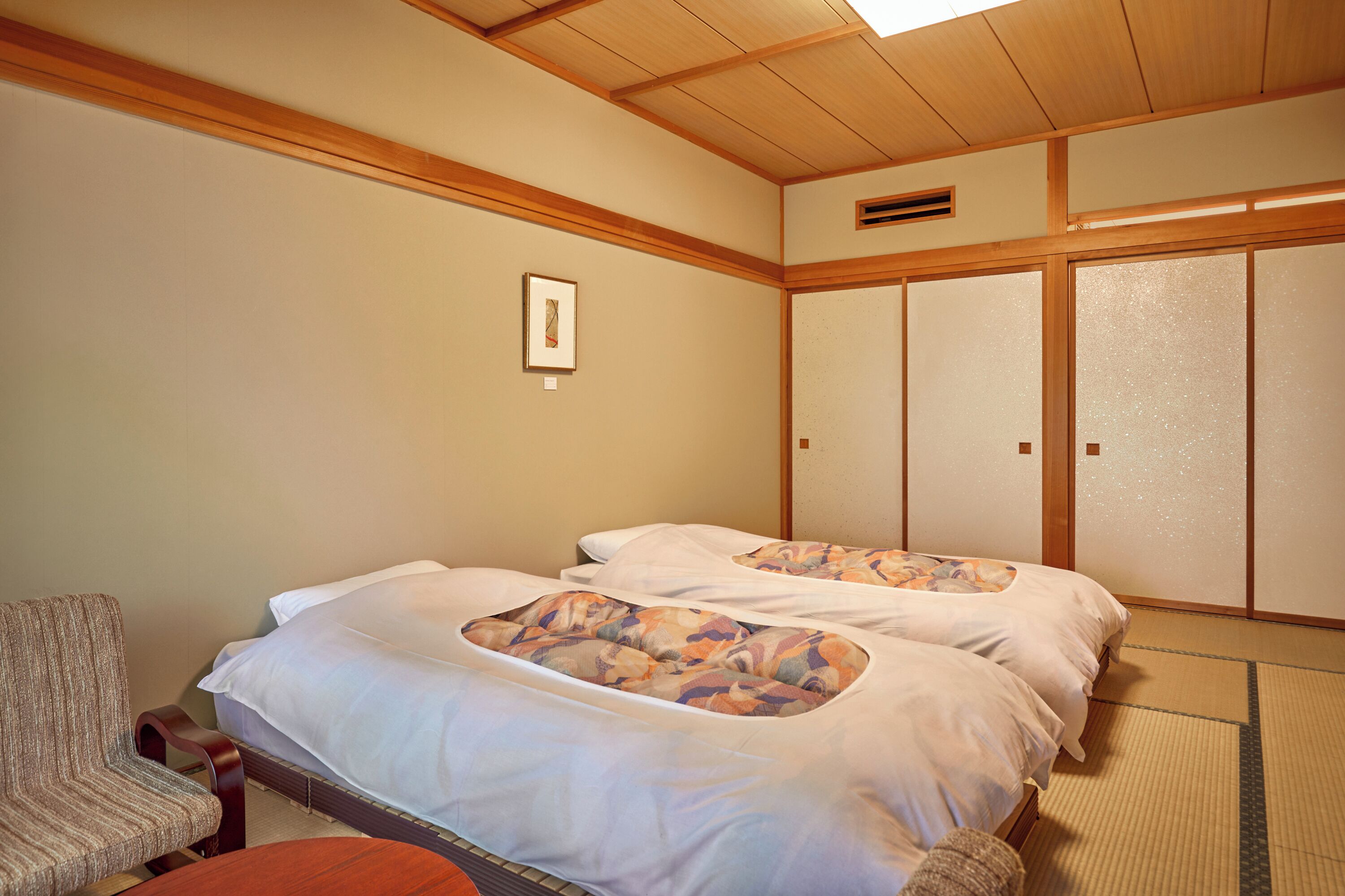 Una habitación tradicional japonesa con dos camas, suelo de tatami y puertas correderas.