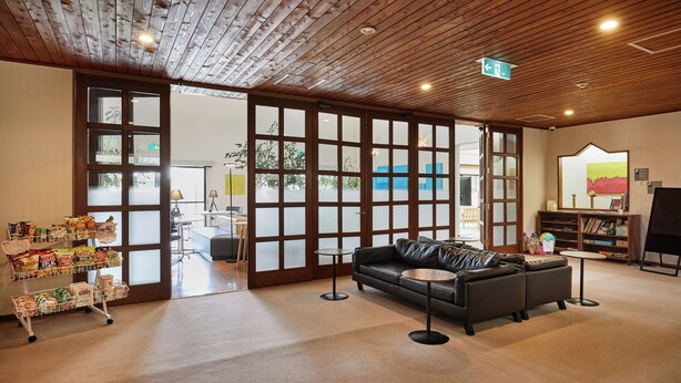 Una habitación amplia con techo de madera, un sofá de cuero negro, una mesita y una bandeja con aperitivos.