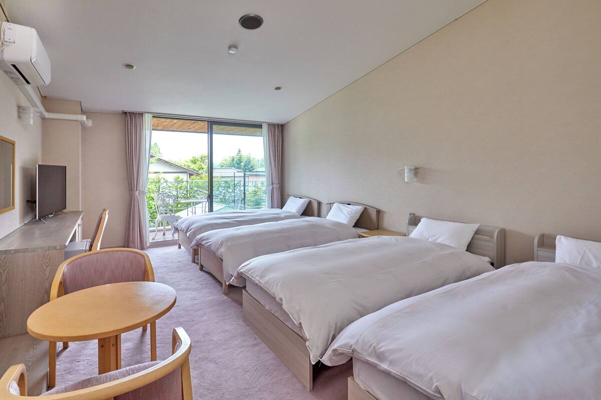 Une chambre d’hôtel avec deux lits, un bureau et une chaise.