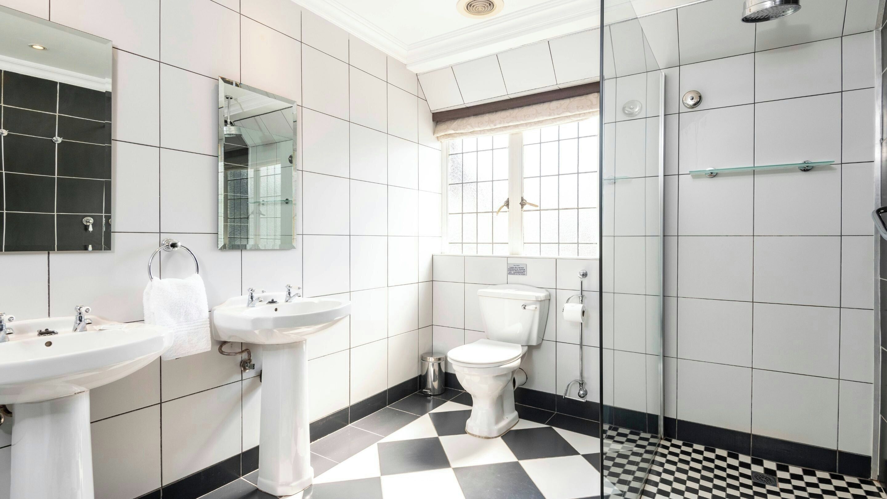 A bathroom with two sinks, a toilet, and a shower.