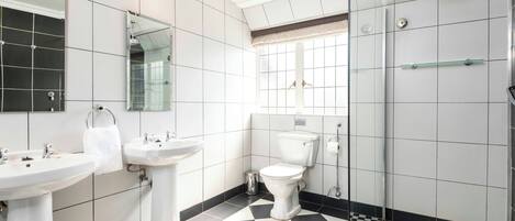 A bathroom with two sinks, a toilet, and a shower.