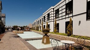 A courtyard with a rectangular pool, a large stone fountain, and outdoor seating. - ANEW Hotel Hilton (Pietermartizburg)