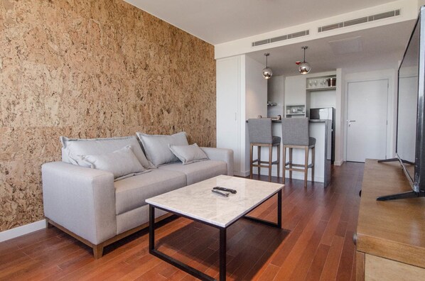 Un salon moderne avec un canapé, une table basse et un coin cuisine à l’arrière-plan.