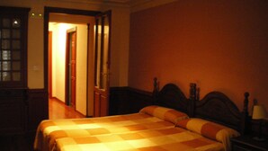 Ein Hotelzimmer mit zwei Betten, Holzkopfteilen und einem Nachttisch mit Lampe.