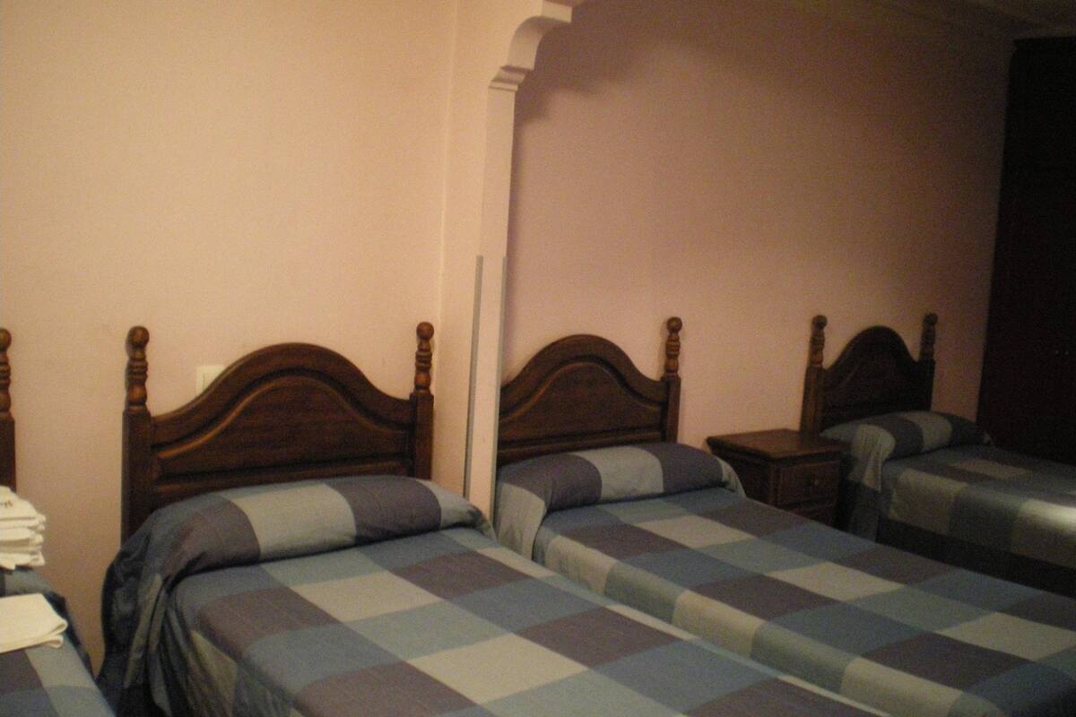 A room with two wooden beds, each with a checkered bedspread.