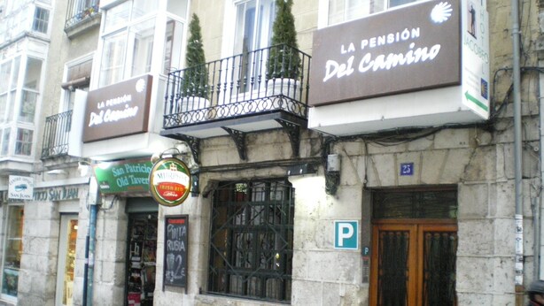 Ein Gebäude mit einem Schild für 'La Pension Del Camino' und einem Schild für 'San Patricio Old Tavern'.