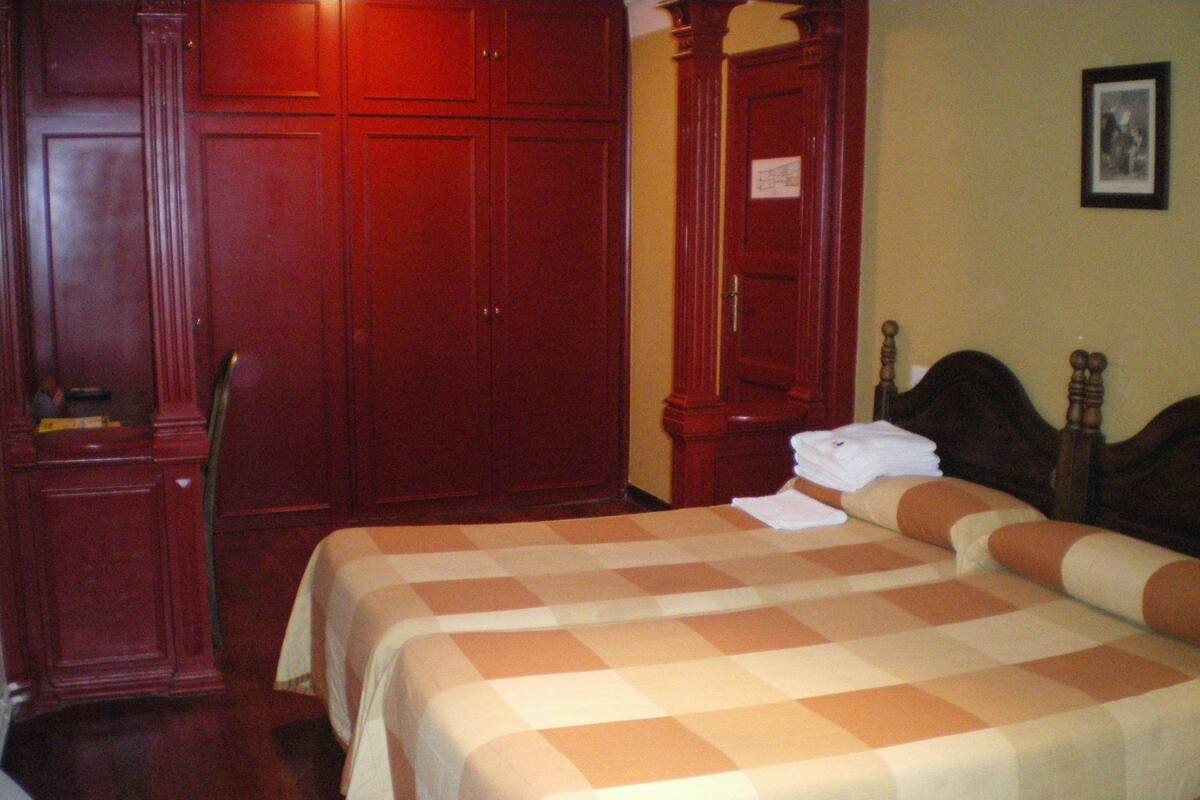 A hotel room with a large bed, a wardrobe, and a framed picture on the wall.