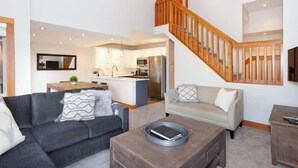 A modern living room with a sofa, coffee table, and a staircase leading to an upper level.