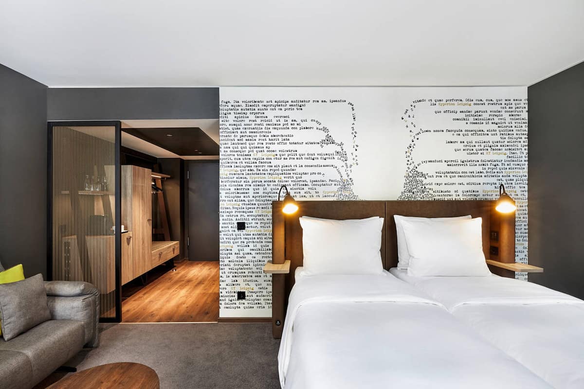 Une chambre d’hôtel moderne avec un grand lit, un canapé et un plancher en bois.