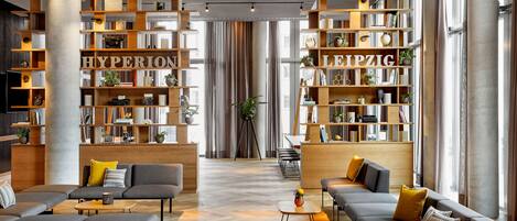 A modern interior with a central seating area, wooden bookshelves, and a herringbone floor pattern.