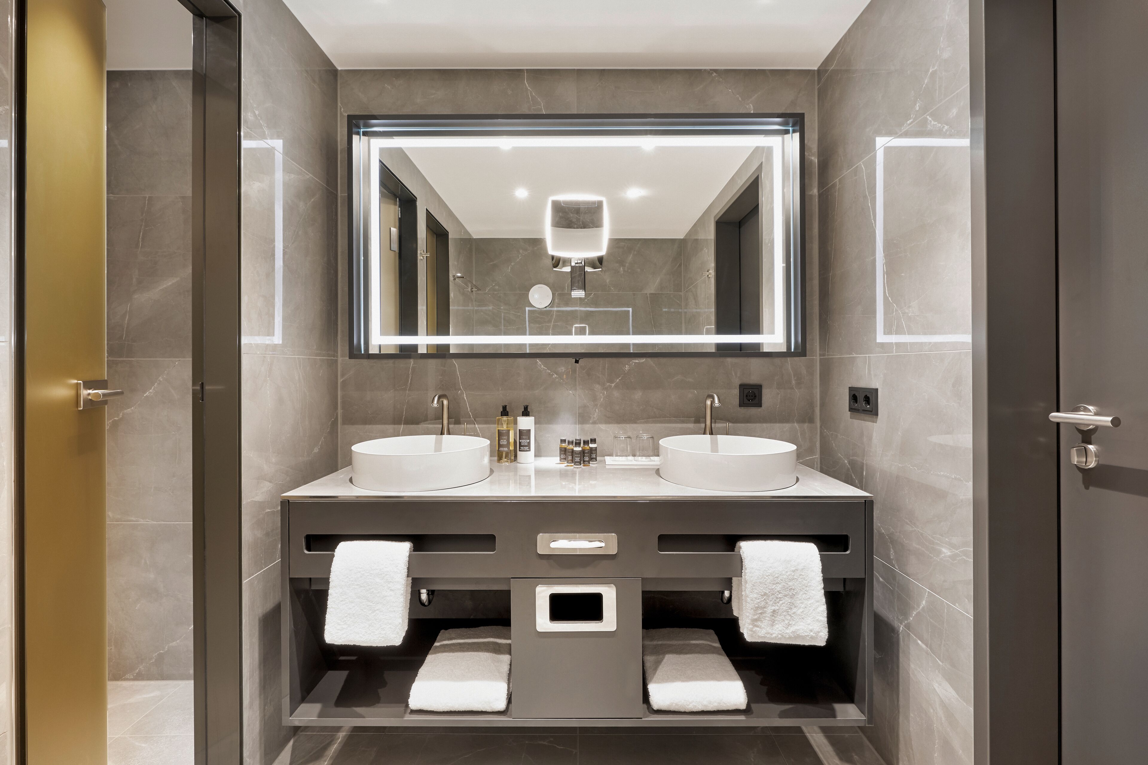 Un baño moderno con dos lavamanos, un espejo grande y un perchero para toallas.