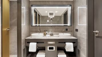 Un baño moderno con dos lavamanos, un espejo grande y un perchero para toallas.