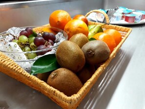 A wicker basket containing kiwis, oranges, and grapes. - Irish College Leuven (Leuven)