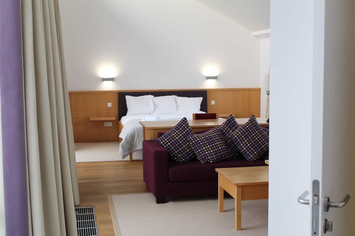 A hotel room with a bed, a sofa, a table, and a nightstand.