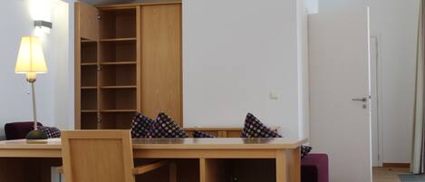 Una habitación con cama, escritorio, silla, armario y lámpara.