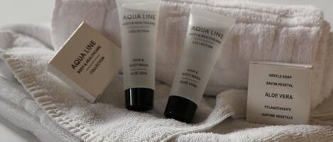 Una toalla blanca con tres botellas de jabón corporal Aqua Line y una caja de jabón Gentle Soap.