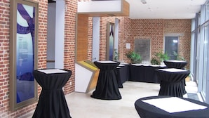 A modern conference room with brick walls, black tables with white centerpieces, and a large window. - Irish College Leuven (Leuven)