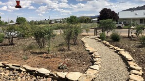 A garden with a gravel path, small trees, and a cactus. - Your Home Away From Home in Escalante (Escalante)