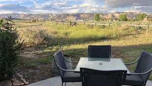 An outdoor patio with a table and chairs, surrounded by a natural landscape with mountains in the background. - Your Home Away From Home in Escalante (Escalante)