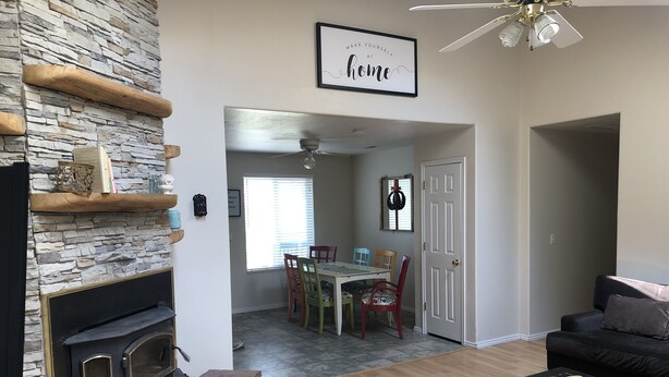A living room with a stone fireplace, a dining area with a table and chairs, and a black sofa. - Your Home Away From Home in Escalante (Escalante)