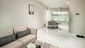 A modern living room with a sofa, a dining area with chairs, and a kitchen in the background. - SSB Residence (Phnom Penh)