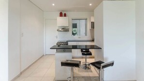 A modern kitchen with a central island, white cabinets, and a stainless steel range hood. - Trendy Barrio Jara apartment (Asunción)