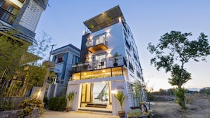 A multi-story building with balconies, a ground entrance, and a scooter parked outside. - Lena Homestay (Da Nang)