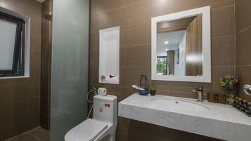 A modern bathroom with a toilet, shower, and sink.